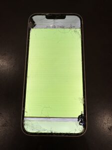 「液晶が緑色に表示され、上下にヒビ割れが広がったiPhone13の修理前の状態」
