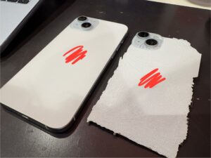 割れて粉々になったiPhone15 Plusの背面パネルと交換前の本体を並べた写真