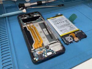 OPPO Reno Aを分解し、内部基板と取り外したバッテリーやパーツが見えている修理作業中の写真。画面交換作業の工程を示す川口市での修理事例。